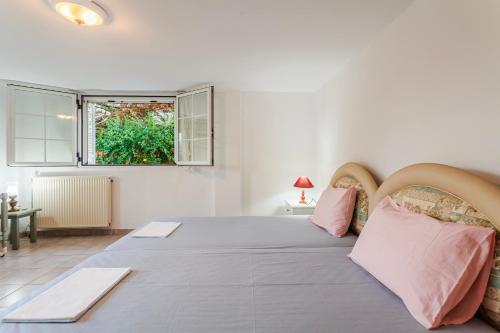 a white bedroom with a large bed with pink pillows at Casa Nebari Seaside Retreats - Fully Equipped, Ideal Spot in Petalidhion