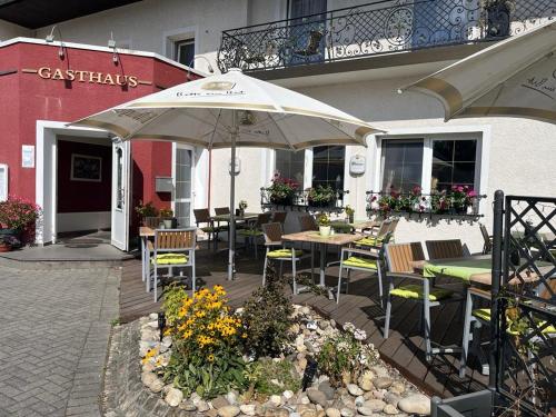un patio con mesas, sillas y una sombrilla en Gasthaus "Zur alten Dorfschmiede", en Metterich