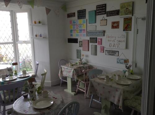 a dining room with tables and chairs and posters on the wall at Green Apple Bed and Breakfast in St Ives