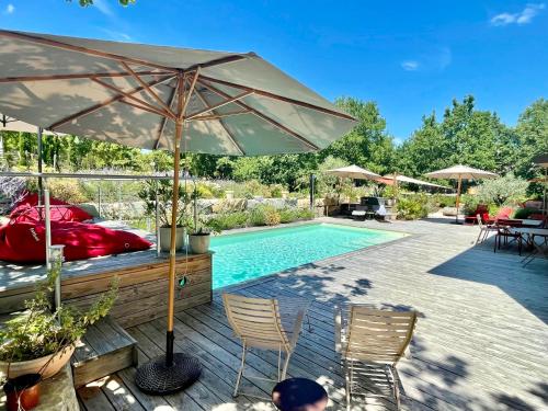 a swimming pool with an umbrella next to a swimming pool at Maison d'Hôtes de Charme Le Clos de la Fontaine Piscine & SPA in Labastide-Marnhac