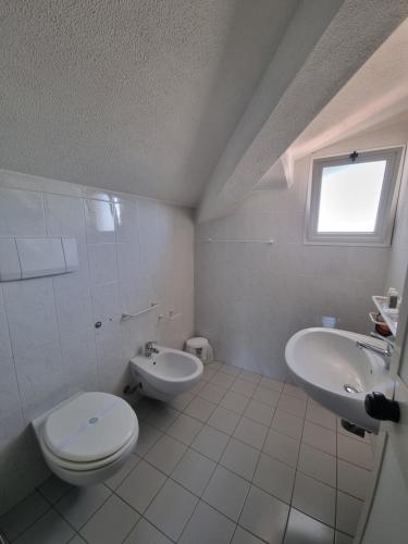 a white bathroom with a toilet and a sink at Hotel Garden Bocca di Magra in Bocca di Magra