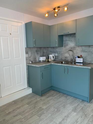 a kitchen with blue cabinets and a sink at Lazy Acres Annex in Langtree