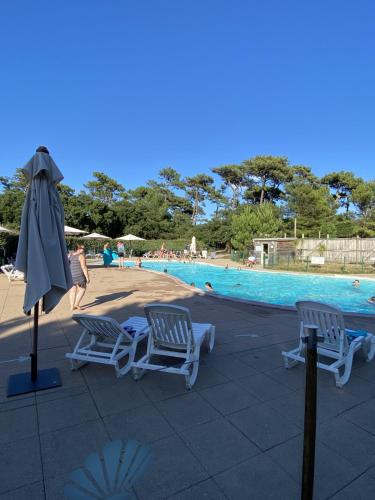 two chairs and an umbrella next to a swimming pool at Village Vacances La Forêt des Landes in Labenne