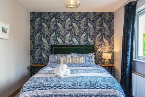 a bedroom with a blue and white bed with a wallpaper at The Arches in Ballycastle