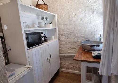 una cocina con un armario blanco con TV. en Rietjiesbos Self Catering, en Graaff-Reinet