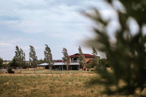 a building in a field with trees in the foreground at Ashwood Groenvlei Boutique Hotel in Bloemfontein