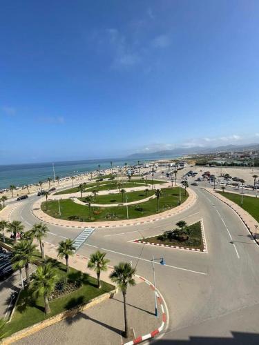 an empty street with palm trees and the ocean at Luxueux appartement avec vue sur mer à Martil in Martil
