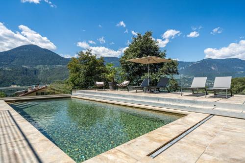a swimming pool with chairs and an umbrella at Videre Penthouse Lodge in Gargazzone
