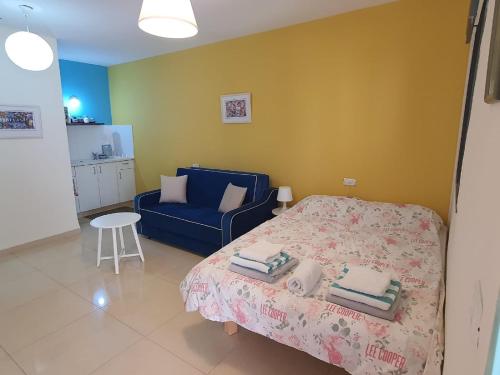 1 dormitorio con 1 cama y 1 sofá azul en יחידת דיור עם בריכה פרטית מפנקת en Rosh Pinna
