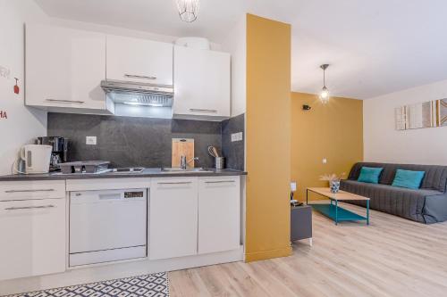 a kitchen with white cabinets and a living room at Appartement en centre piétonnier proche de la gare in Thionville