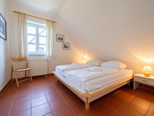- une chambre avec un grand lit blanc et une chaise dans l'établissement Feriendorf Rugana - Budget Appartement mit 1 Schlafzimmer A39, à Dranske