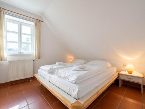 a large white bed in a room with a window at Feriendorf Rugana - Moderne Komfort Ferienwohnung mit 1 Schlafzimmer C02 in Dranske