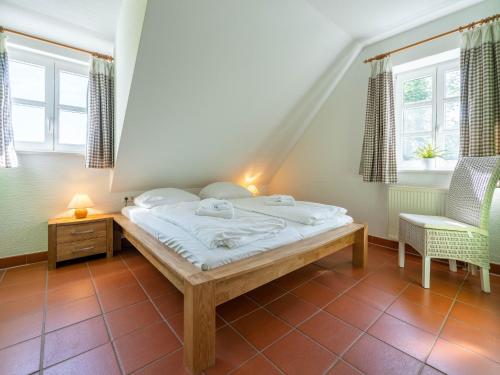 ein Schlafzimmer mit einem Bett und einem Stuhl und Fenstern in der Unterkunft Feriendorf Rugana - Komfort Appartement mit 2 Schlafzimmern und Terrasse C48 in Dranske