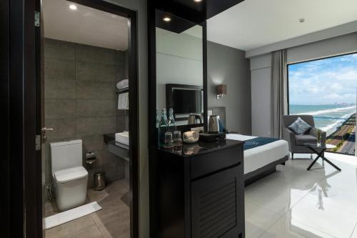 a hotel room with a bathroom with a bed and a television at MaRadha Colombo in Colombo