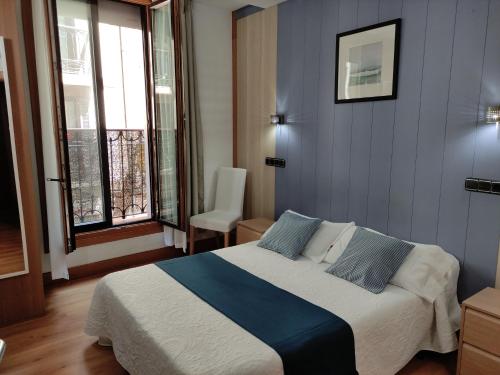 1 dormitorio con 1 cama grande, paredes y ventanas azules en AlojaDonosti City Center, en San Sebastián
