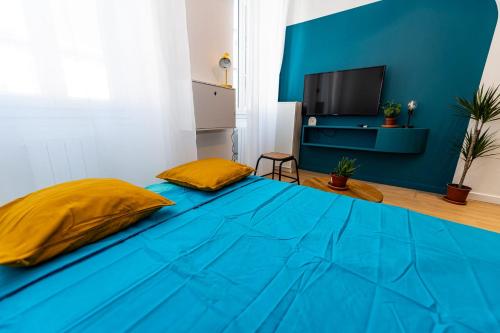 ein blaues Bett mit zwei gelben Kissen in einem Zimmer in der Unterkunft Noa : Joli studio cosy avec chambre in Marseille