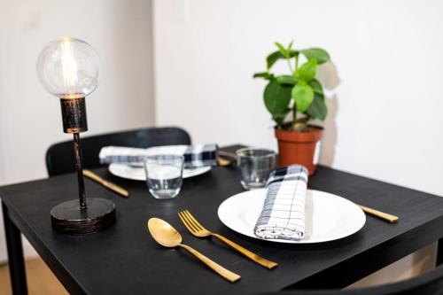 馬賽的住宿－Noa : Joli studio cosy avec chambre，一张带盘子和餐具的黑桌和一盏灯