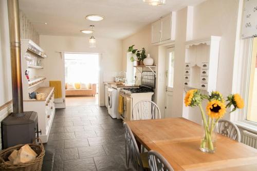a kitchen with a table with a vase of flowers on it at The Cheesery in Chinley