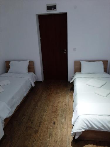 two beds in a room with white walls and wooden floors at The Cohen's Guest House in Kyustendil