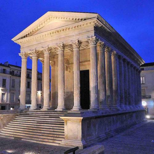 a large white building with columns and steps at night at Roma Divine home cinéma et jardin in Nîmes
