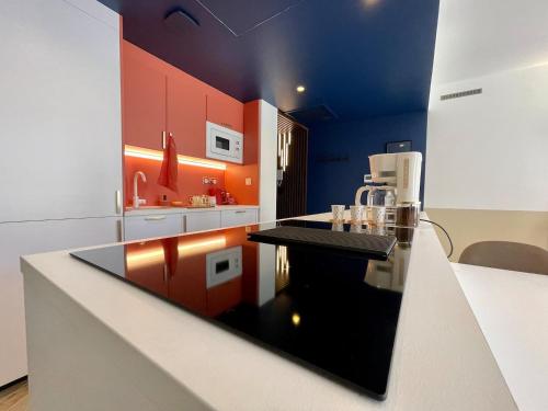 a kitchen with orange and blue walls and a counter at Roma Divine home cinéma et jardin in Nîmes