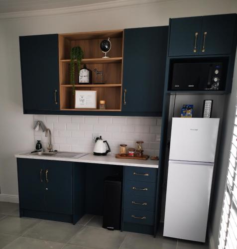 a kitchen with blue cabinets and a white refrigerator at 10 Jock Meiring Guesthouse Unit 2 in Bloemfontein
