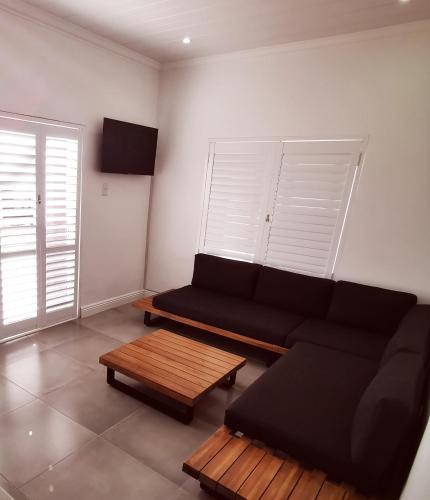 a living room with a black couch and a coffee table at 10 Jock Meiring Guesthouse Unit 2 in Bloemfontein