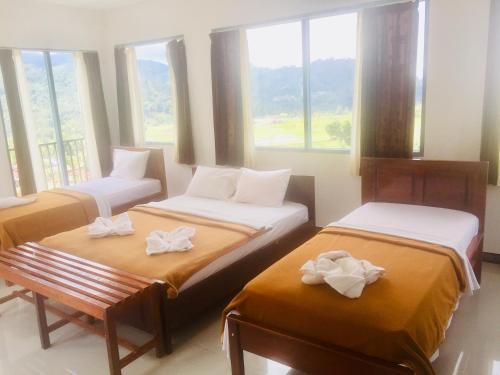 a room with two beds and a bench and windows at Bintang by Tobias Lodge Cafe & Restaurant in Kelimutu