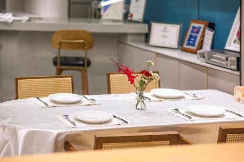 a table with plates and a vase of flowers on it at Shenzhen ALLIN Space to time in Shenzhen