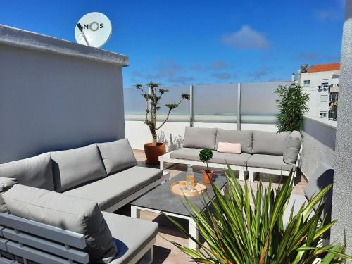 a patio with couches and a table on a balcony at Sitius 5B - NEW seaview apartment with rooftop terrace in historical centre Sitio da Nazaré in Nazaré