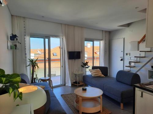 a living room with a blue couch and a table at Sitius 5B - NEW seaview apartment with rooftop terrace in historical centre Sitio da Nazaré in Nazaré