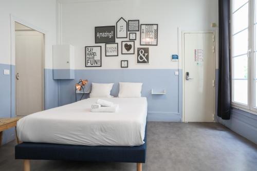 une chambre avec un grand lit blanc avec une tête de lit bleue dans l'établissement WS Montorgueil-Louvre, à Paris