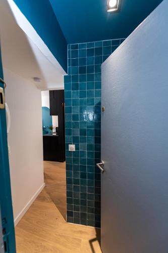 La salle de bains est pourvue d'une douche et de carrelage bleu. dans l'établissement Noa : Joli studio cosy avec chambre, à Marseille