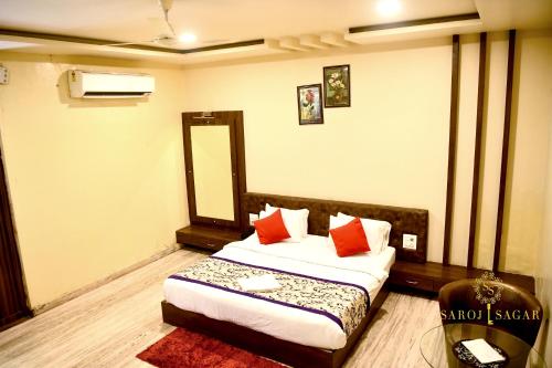 a bedroom with a bed with red pillows and a mirror at Hotel Saroj Sagar in Sāgar