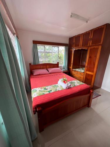 a bedroom with a bed with red sheets and a window at Hill Bottom Accommodation in Suva