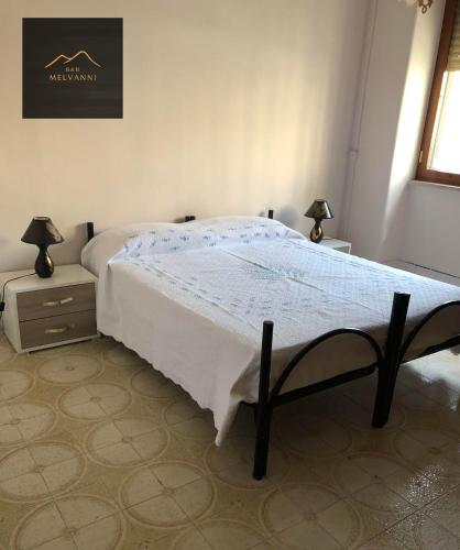 una camera con un letto, due lampade e una finestra di Melvanni a Pomigliano dʼArco