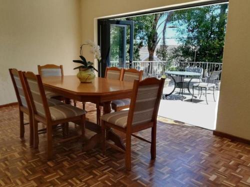 a dining room with a table and chairs and a patio at Cape Dawn Guest House in Parow