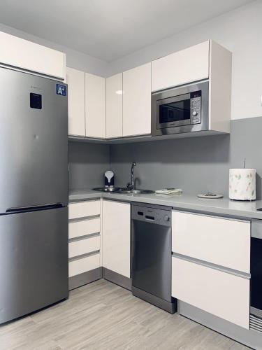 a kitchen with white cabinets and a stainless steel refrigerator at Apartamento La Cueva, Artenara By Artenatur in Artenara
