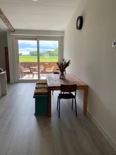 a dining room with a table and a large window at Bij het meertje! in Dirkshorn