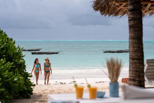 two women in bikinis walking on the beach at The Loop Beach Resort in Jambiani