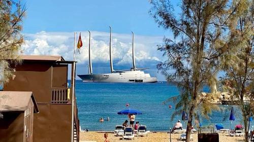 a boat in the water with people sitting under an umbrella at Tsokkos Gardens Hotel in Protaras