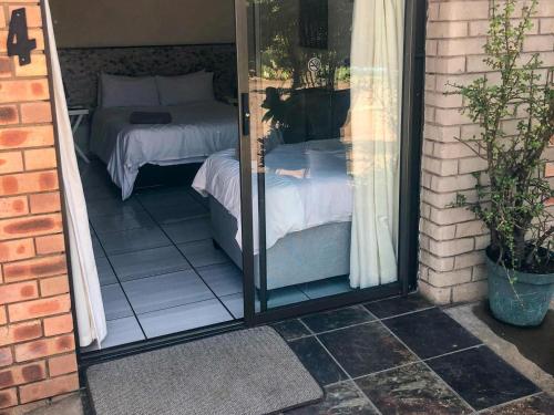 a glass door leading to a bedroom with a bed at Jozini Guesthouse in Jozini