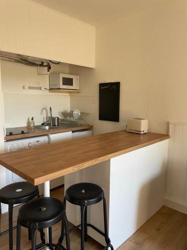 a kitchen with a wooden counter and stools in it at Appartement à Seignosse océan 2 chb et jardin in Seignosse