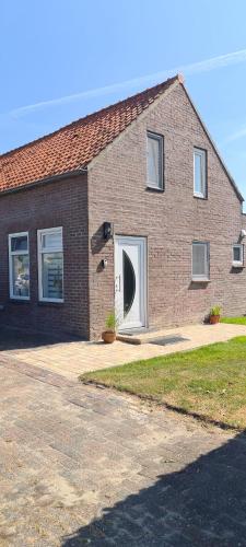 a brick house with a door with a window at Maisonnette Slijkplaat 18 in Hoofdplaat