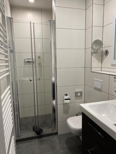 uma casa de banho com um chuveiro, um WC e um lavatório. em Garni Hotel Eastside em Magdeburg