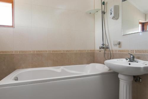 a bathroom with a white tub and a sink at Семеен хотел Golden Place in Sozopol