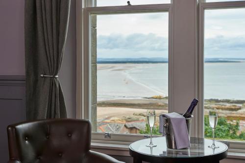a table with wine glasses and a chair in front of a window at Hotel Du Vin, St Andrews in St. Andrews