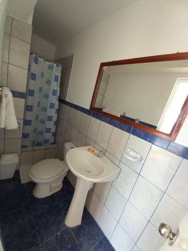 a bathroom with a sink and a toilet and a mirror at Hostal Los Frayles in Paracas