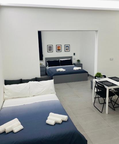 a bedroom with two beds and a table and a bed at Sicilian Rooms in Avola