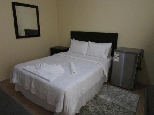 a bedroom with a large white bed with a mirror at Lalamnandzi1 in White River